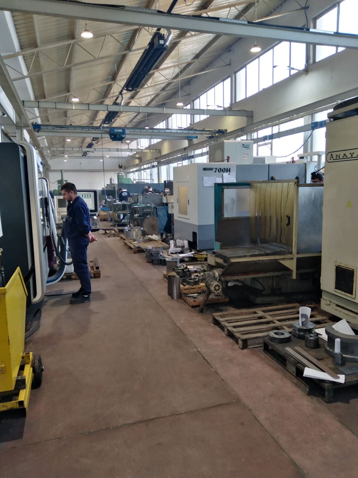 A row of CNC machining centres in the hall, with pallets of staged parts